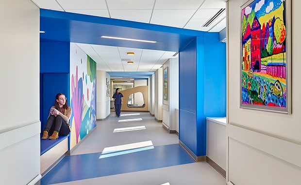 FEatured image showing a teenager sitting in a corridor nook in a bright and cheerful pediatric hospital